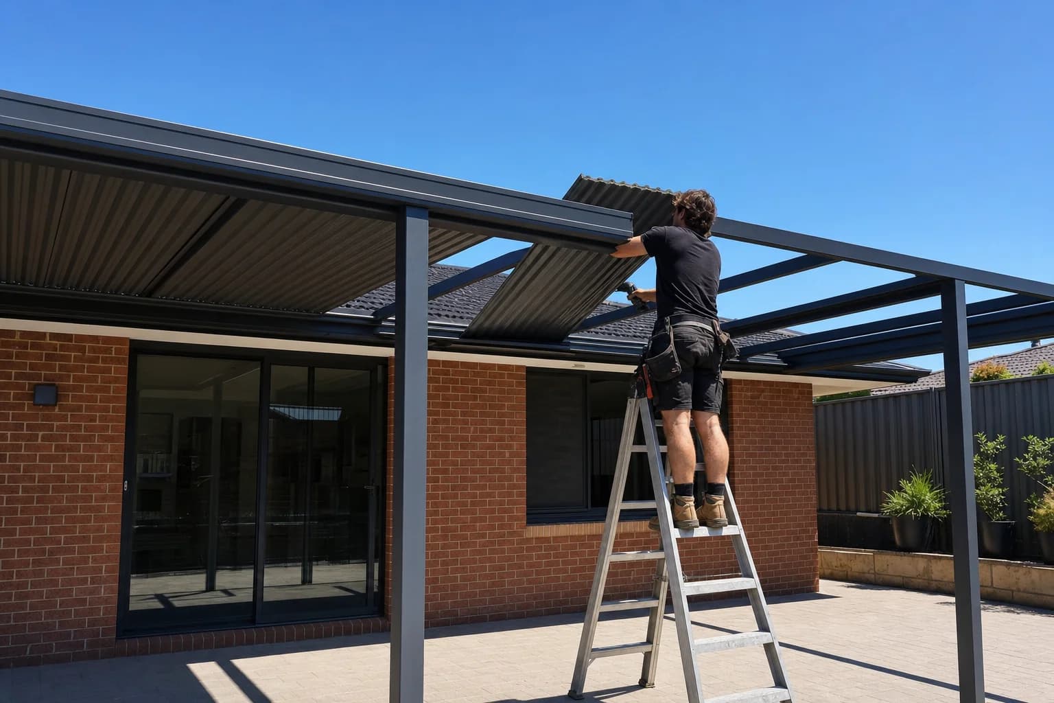 Worker fitting new Colorbond roof sheeting to a patio frame in Joondalup